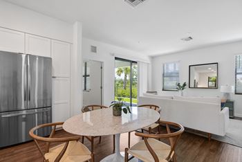 A kitchen with a refrigerator and a table with four chairs